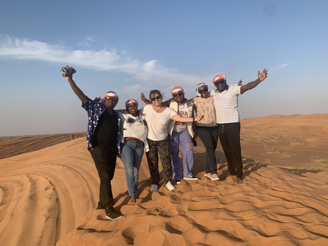 Group of people joyfully posing on a desert dune.