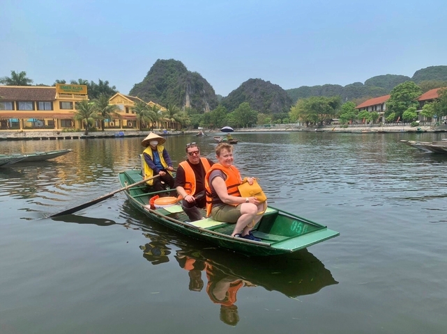 People in a boat, wearing life vests, on a calm river.