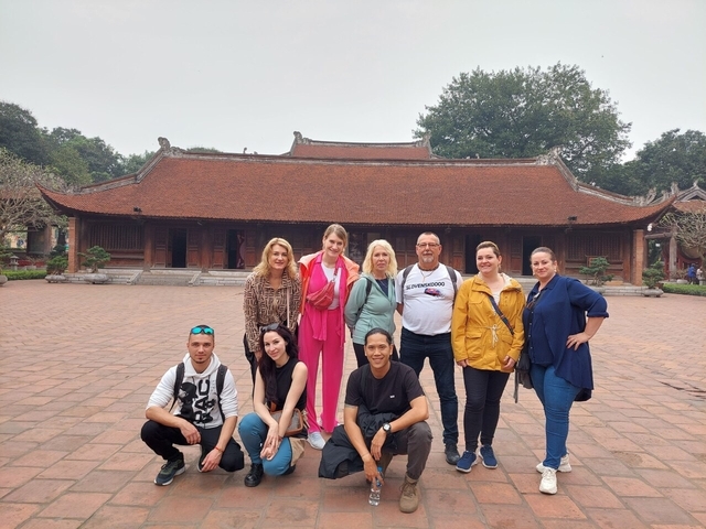 Group of people posing in front of a traditional building.