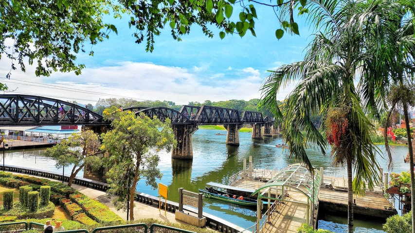       Old iron bridge over a river with lush greenery.
  