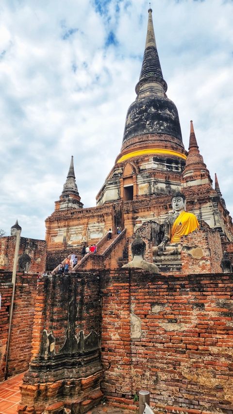       Buddhist temple with large Buddha statues and people.
  