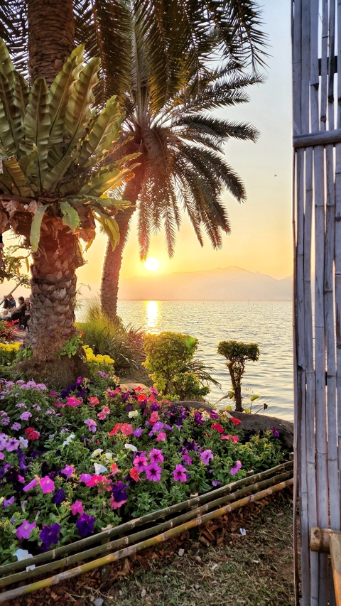       Scenic lake view with sunset and silhouetted mountains.
  
