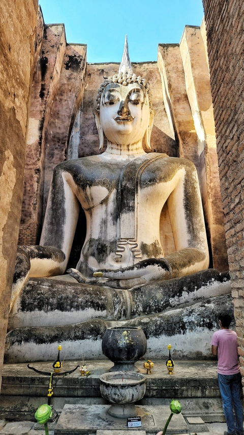       Ancient seated Buddha statue in a historical setting.
  