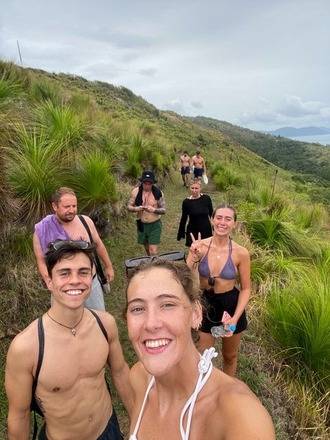 Hikers on a grassy trail with foliage.