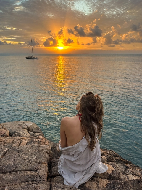 Woman looking out at a sunset over the water.