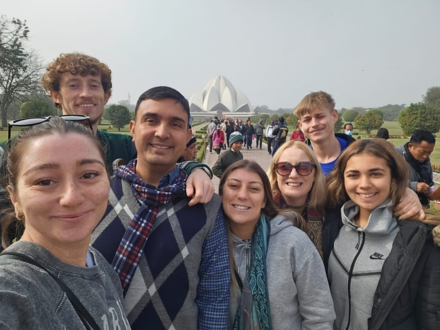       A group of people posing in front of a lotus-shaped building.
  
