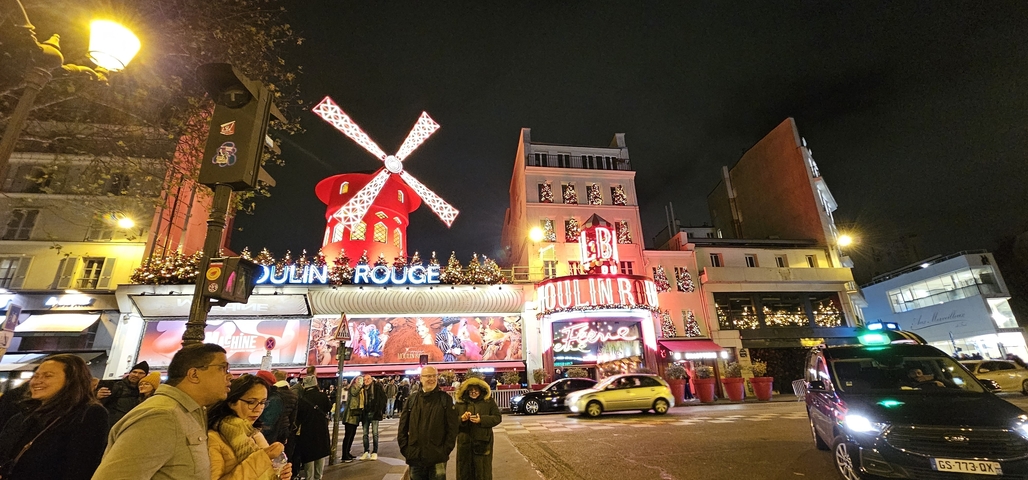       The illuminated facade of the Moulin Rouge at night.
  