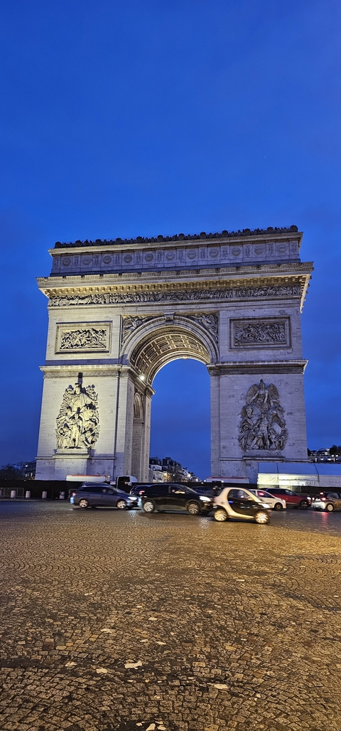       The Arc de Triomphe at dusk with detailed carvings visible.
  