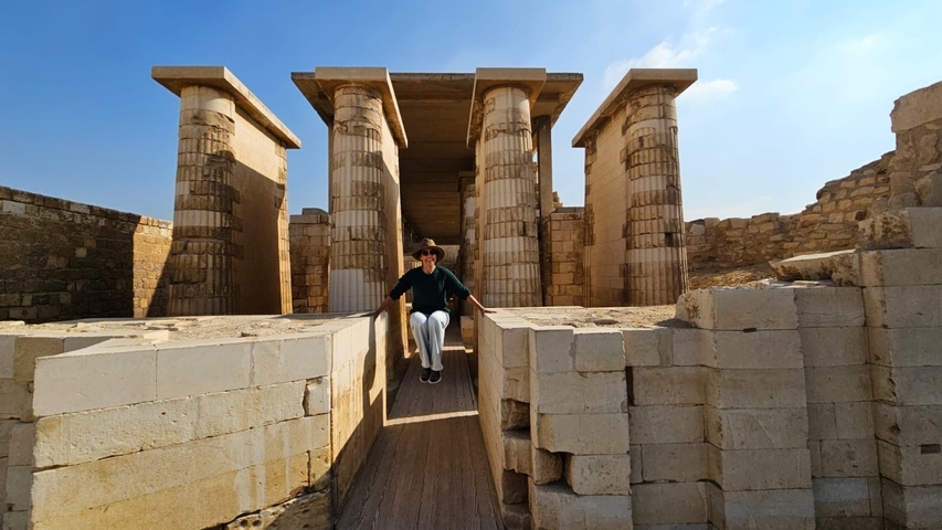       Person sitting on a walkway in front of ancient columns.
  