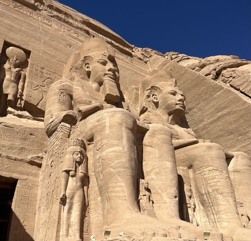       Close-up of large statues carved in stone against a blue sky.
  