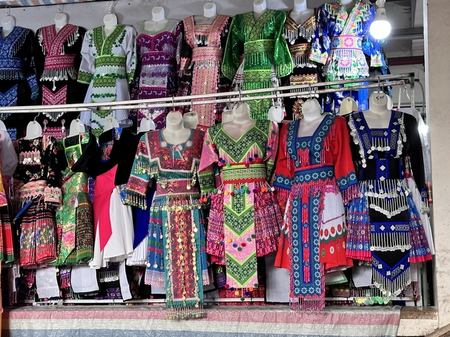       Colorful traditional dresses hanging for display.
  