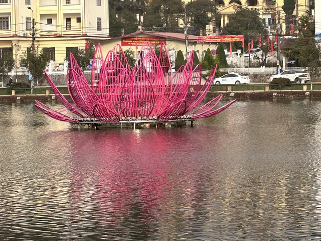       Large pink sculpture resembling a lotus in a lake.
  