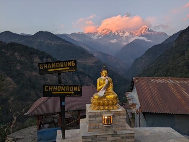 A golden Buddha statue with mountainous scenery in the background.