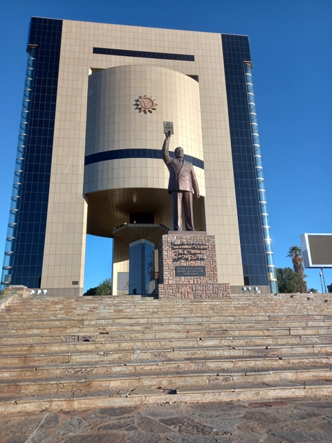 Statue of a prominent figure in front of a modern building.