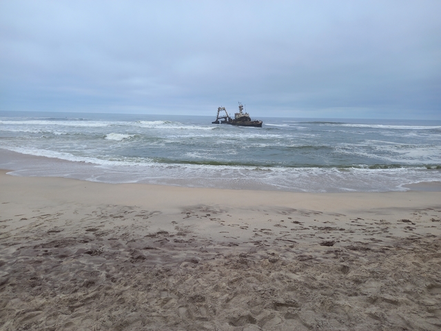 A shipwreck on a beach with waves crashing in the background.