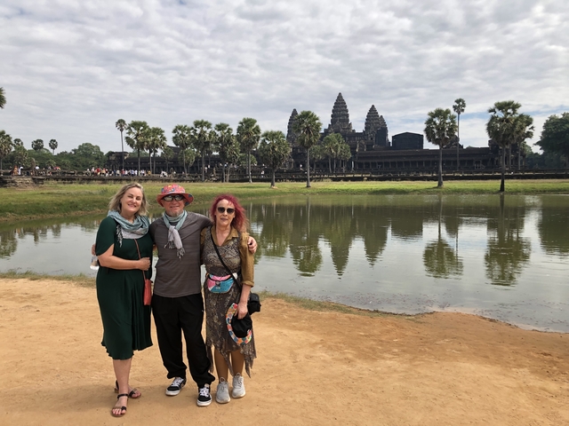       Group posing in front of Angkor Wat with reflection in the water.
  
