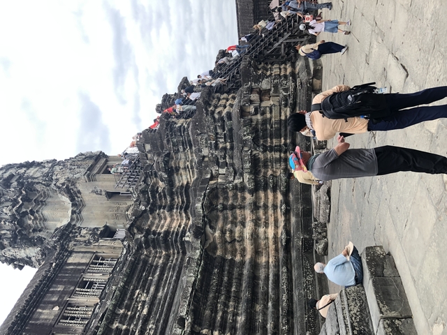       Visitors at Angkor Wat examining stone carvings.
  