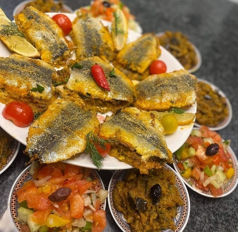 Plate of grilled sardines adorned with vegetables.