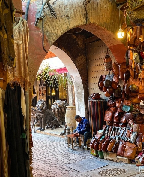 Moroccan market scene with leather goods and a vendor.