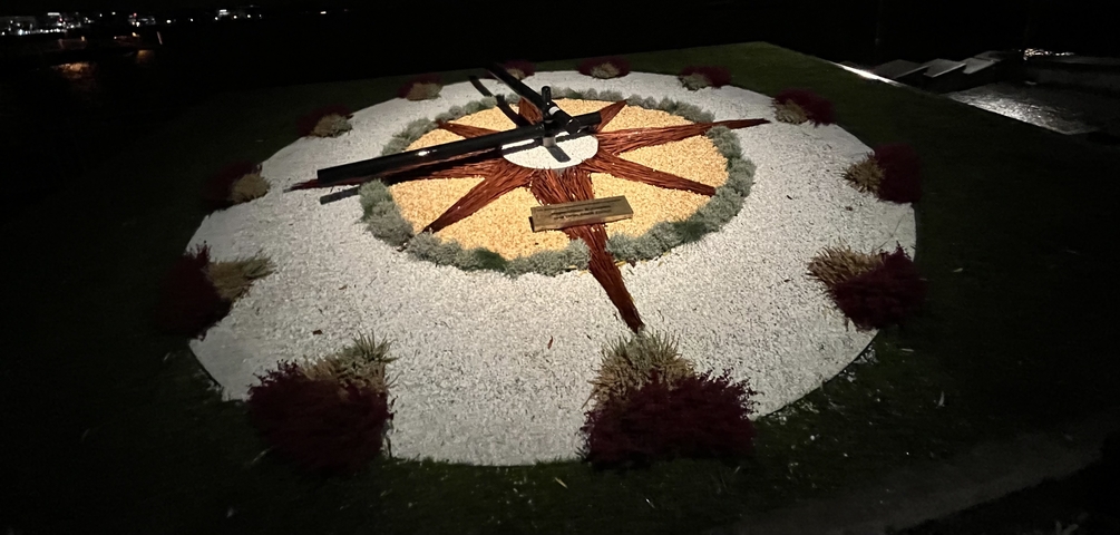       Decorative garden clock with various colored stones and plants.
  