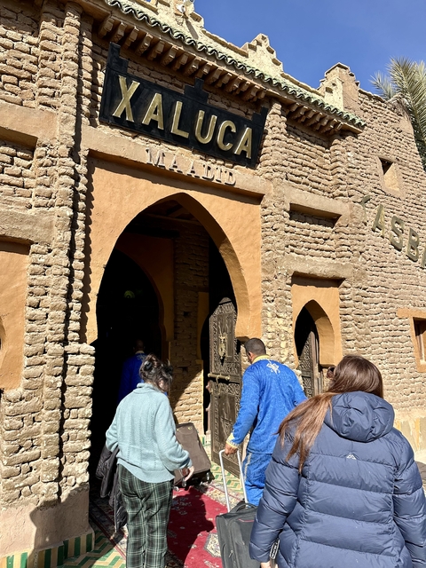       People entering a traditional building with an arched entrance.
  