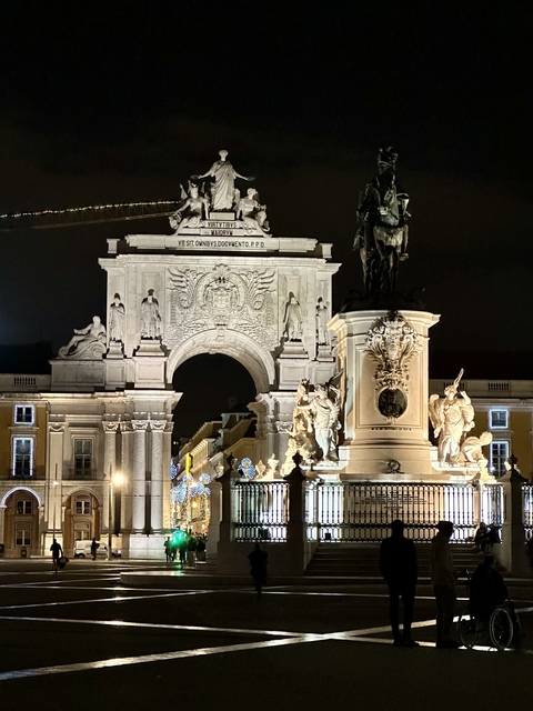       Arch with statues and detailed carvings against the night sky.
  