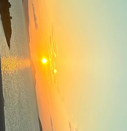 Upside-down image of a colorful sunset over the sea.