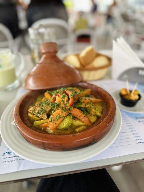       A Moroccan tagine dish with vegetables served on a table.
  