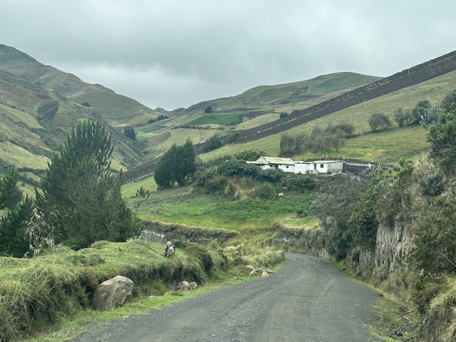       Rural landscape with green hills and a small house.
  