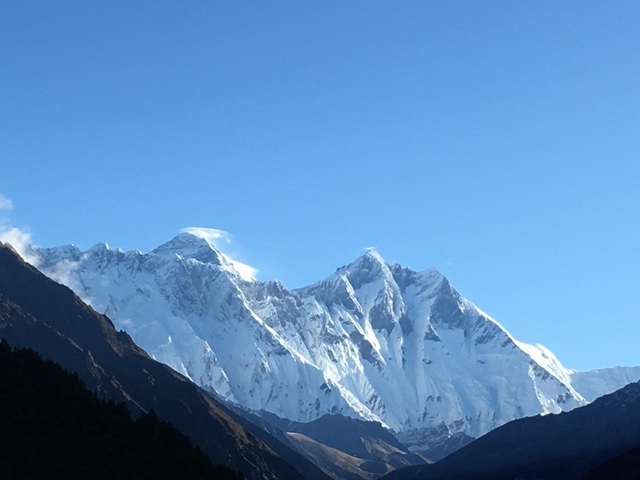 Majestic mountain range covered in snow under a blue sky.