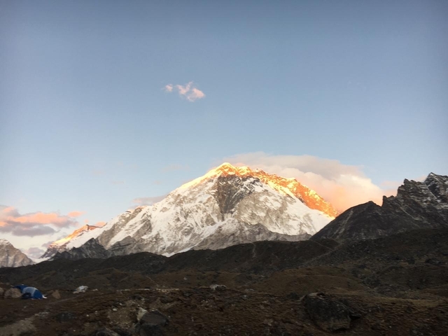 Sunlit snowy peak of a mountain against a clear sky.