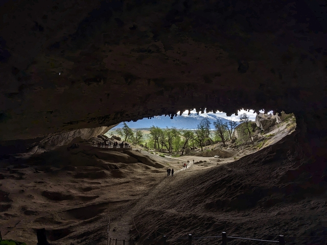       Cave opening view showing a forested landscape beyond.
  