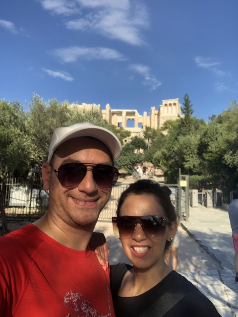       Two people posing with an ancient structure in the background.
  