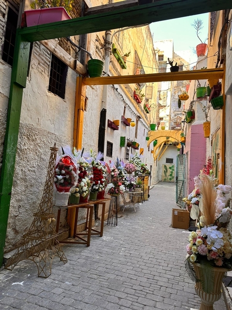 Flower-lined alleyway with colorful architecture.