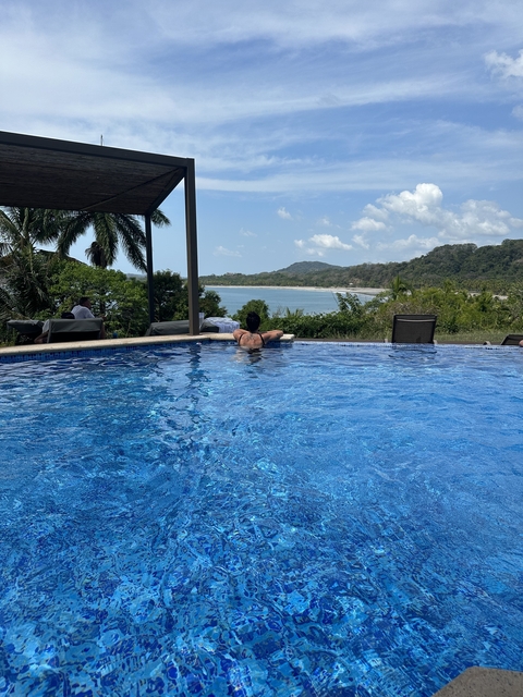       Person relaxing in an infinity pool overlooking a beach.
  