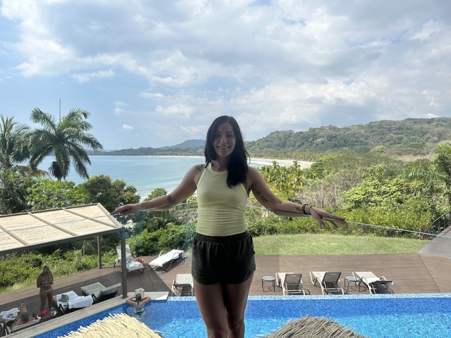       Woman posing with a beach view in the background.
  