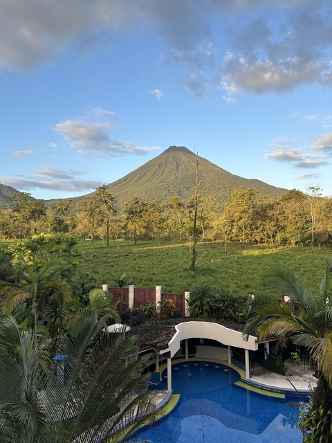       View of a lush landscape with a large volcano.
  