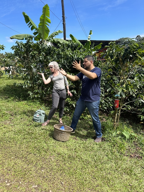       Two people engaging in a gestural expression surrounded by greenery.
  