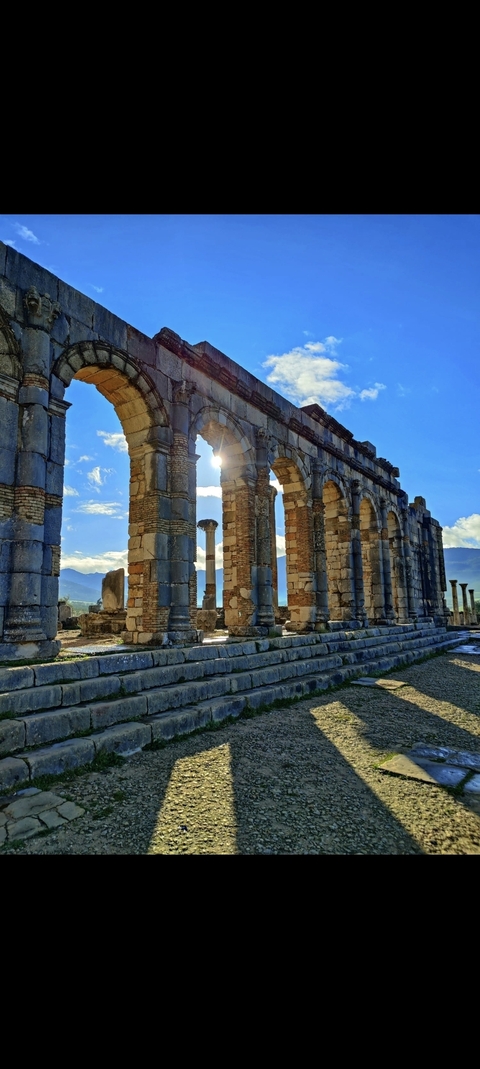 Ancient ruins with arches and a scenic backdrop.