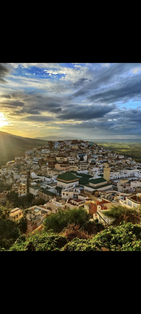 Panoramic view of a city on a hill during sunset.