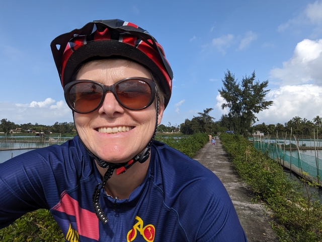 Person smiling while biking on a rural road.