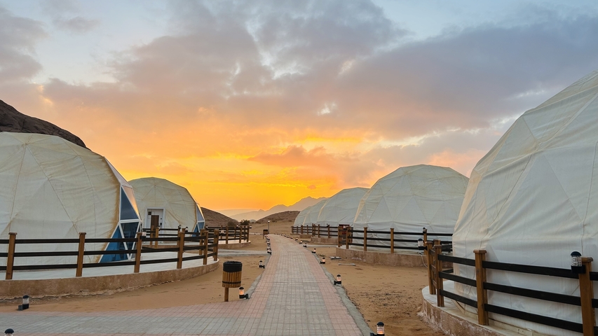 Pathway leading to dome-shaped tents with sunset sky