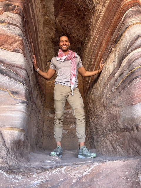       Person standing in narrow sandstone passageway
  