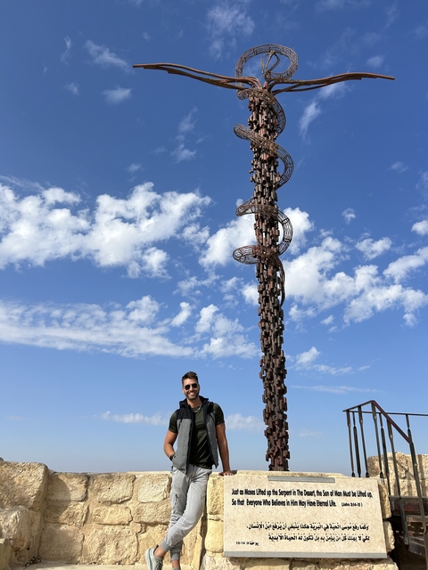 Person with tall metal sculpture against a blue sky