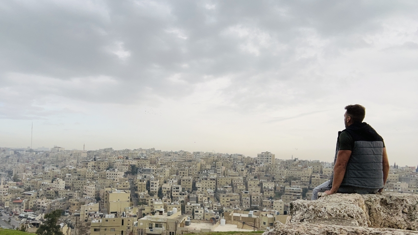       Person overlooking a cityscape with dense buildings
  