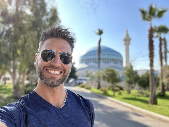       Person smiling with a mosque in the background
  