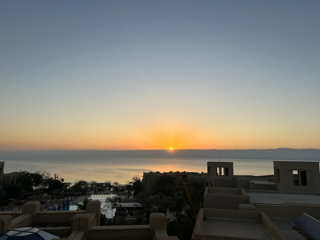       Sunset view over a coastal area with buildings and horizon
  