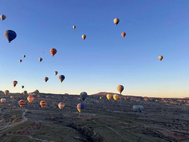       Many hot air balloons over a rocky landscape
  