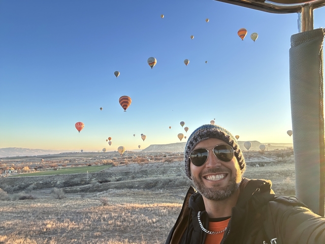       Person in a hot air balloon with balloons in the background
  