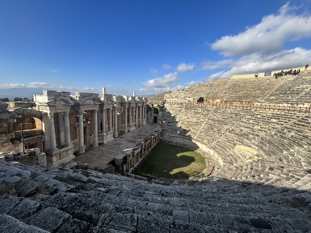       Ancient amphitheater with people exploring
  